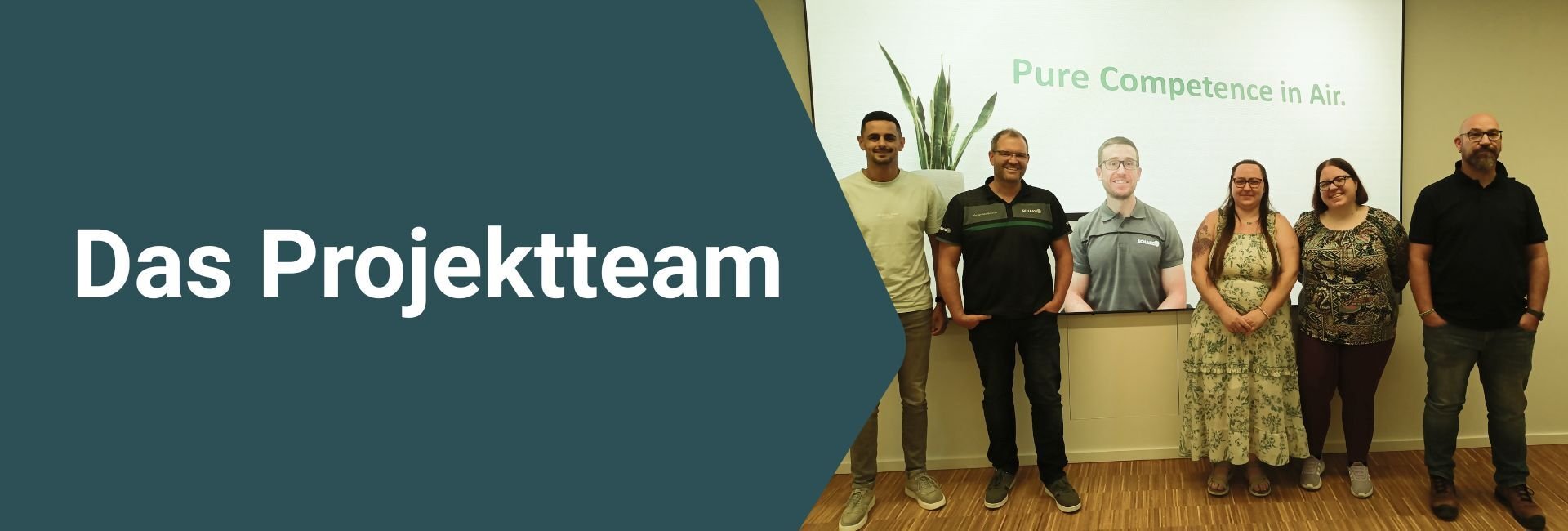 Gruppenfoto des Projektteams: mehrere Personen stehen vor einer Präsentationswand; links steht der Schriftzug „Das Projektteam“.